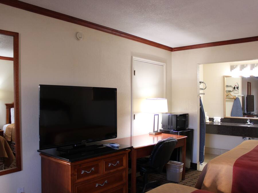 Una habitación de hotel con televisión, escritorio, silla y cama.