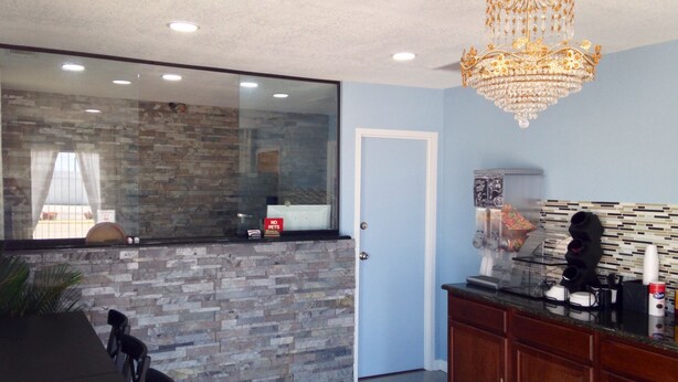A modern kitchen with a stone backsplash, a wooden cabinet, and a chandelier. - Sanger Inn (Sanger)