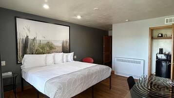 A bedroom with a bed, a dining table, and a kitchen area.
