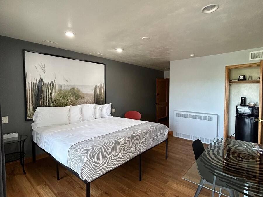 A bedroom with a bed, a dining table, and a kitchen area.