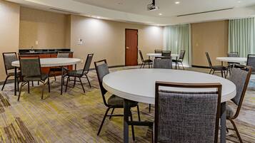 A conference room with a large oval table, smaller round tables, and several chairs.