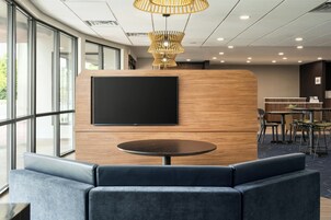 Un moderno vestíbulo de hotel con una gran pantalla de televisión, una mesa redonda y asientos cómodos.