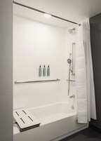 Un baño moderno con bañera, ducha y barras de apoyo.