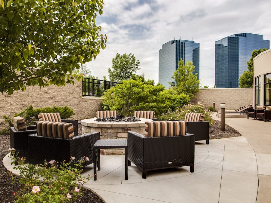 Un patio exterior con mobiliario de mimbre, una chimenea y vistas a dos rascacielos.