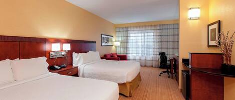 A hotel room with two beds, a desk, a chair, a lamp, and a picture on the wall.