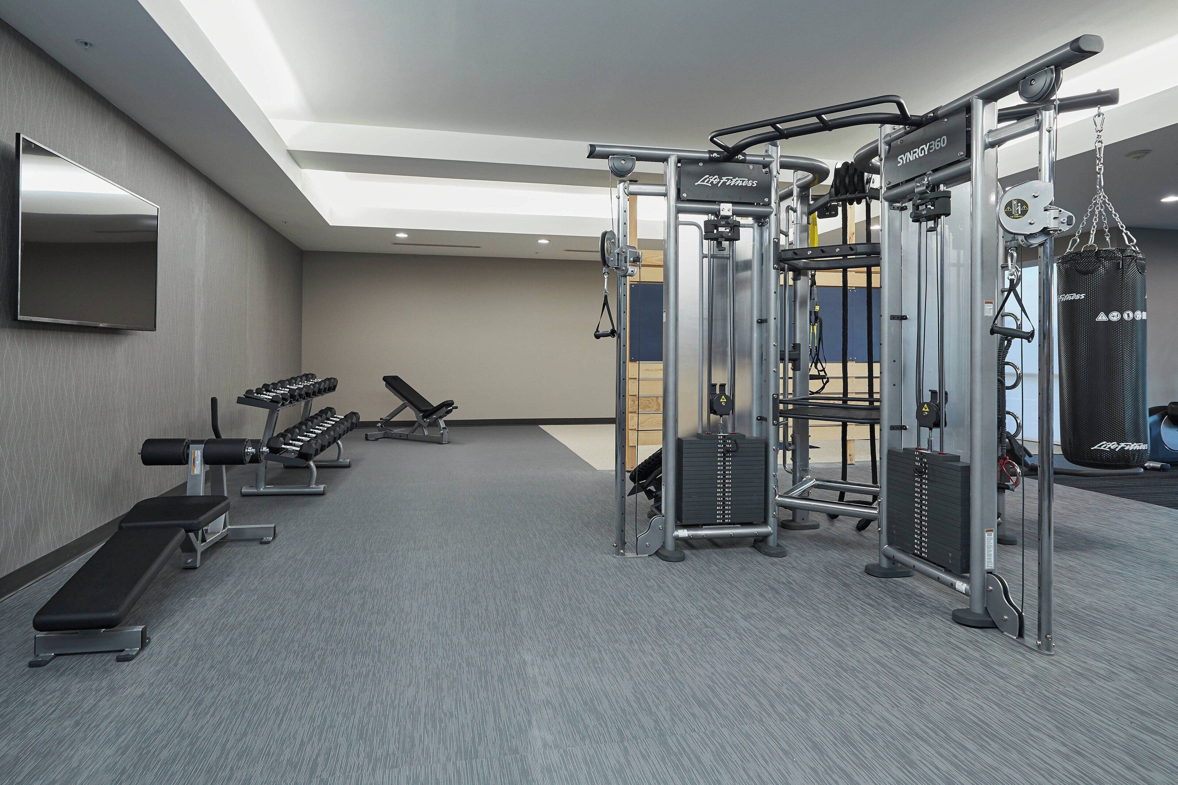 A gym with weight machines, benches, and a punching bag.