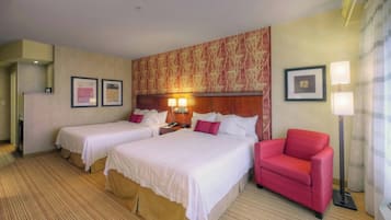 A hotel room with two beds, a red armchair, and a large patterned wall.
