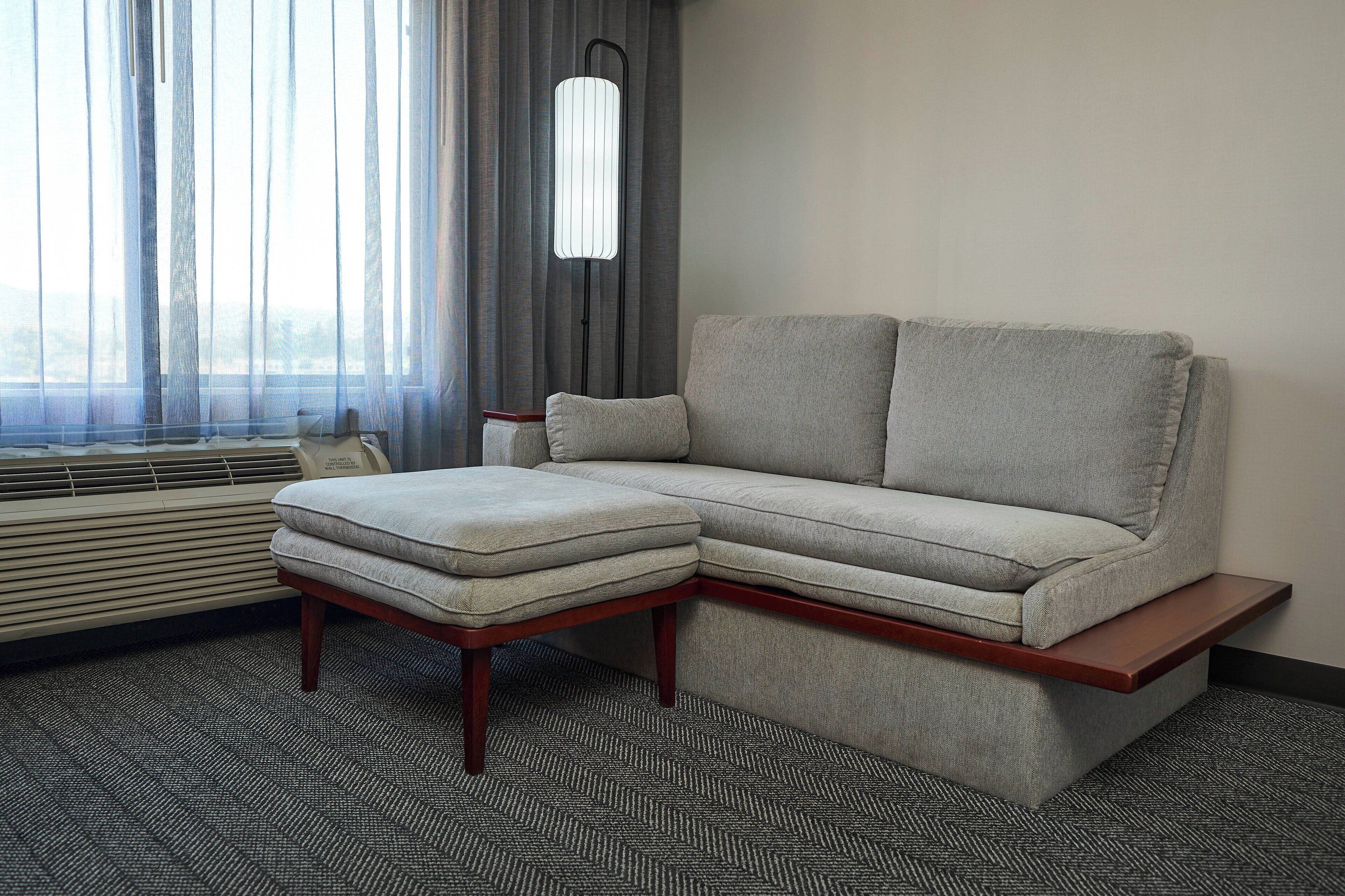 A modern living room with a grey sectional sofa, a wooden coffee table, and a floor lamp.