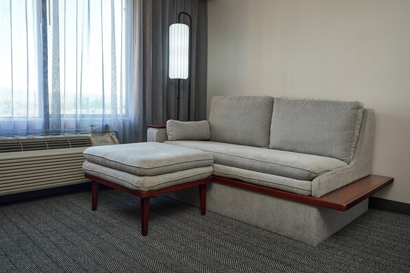 A modern living room with a grey sectional sofa, a wooden coffee table, and a floor lamp.