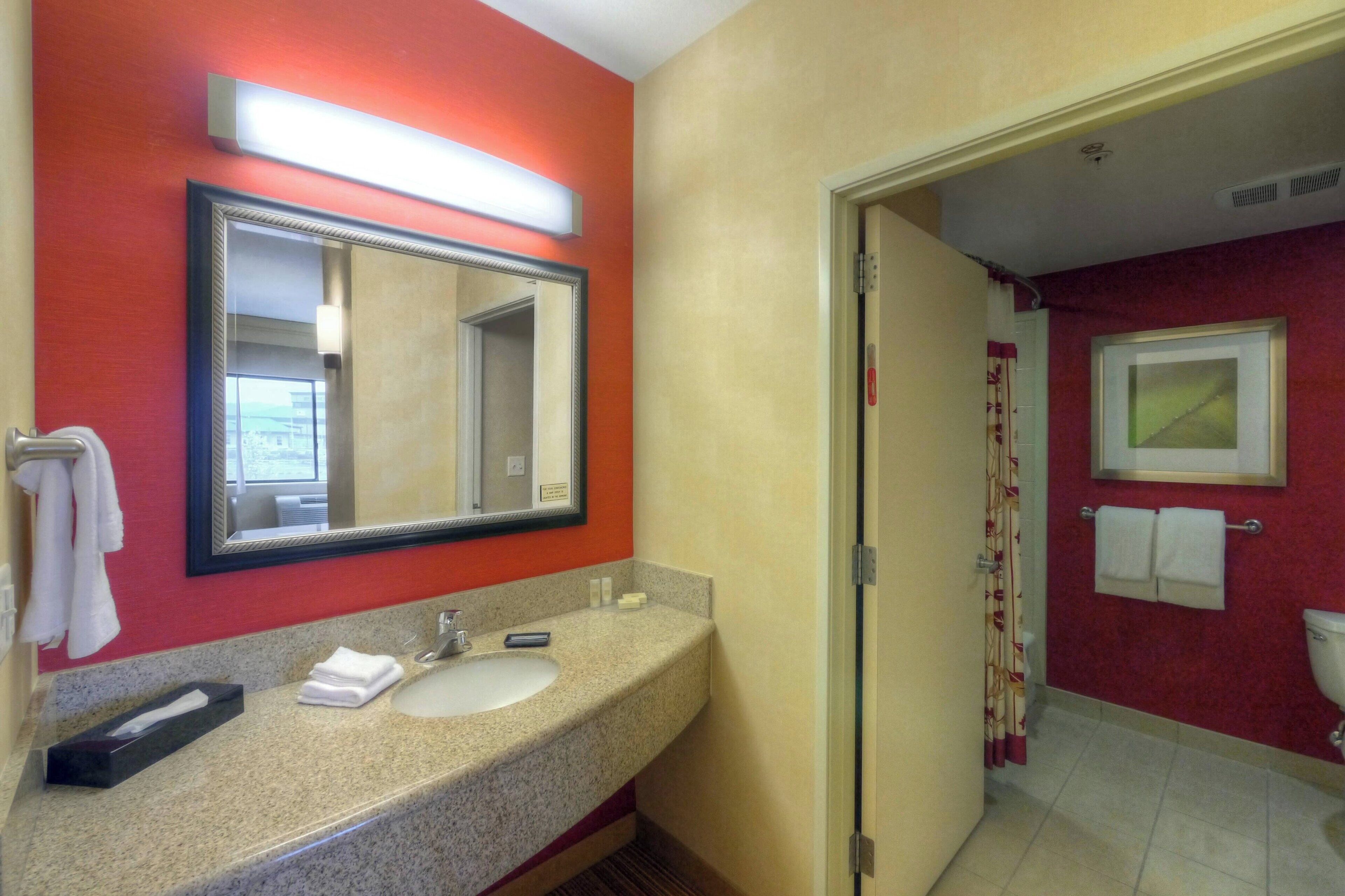 A bathroom with a granite countertop, a sink, a mirror, and a toilet.