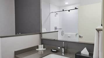Une salle de bain moderne avec un grand miroir, un lavabo, un porte-serviettes et un espace douche.