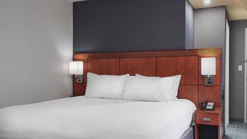 A hotel room with a large bed, wooden headboard, bedside lamps, and a telephone on a wooden nightstand.