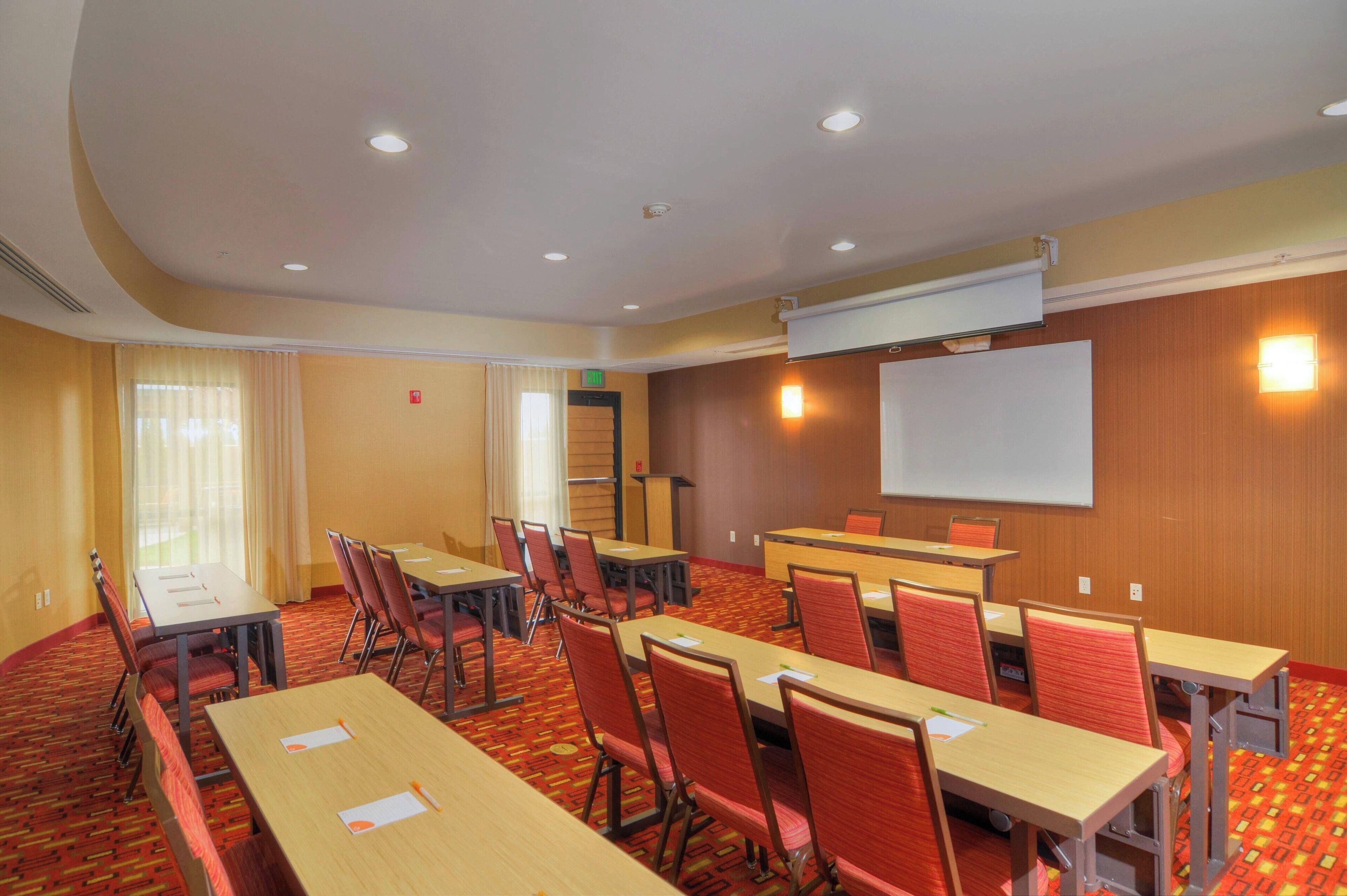 A conference room with tables and chairs, a projector screen, and a podium.