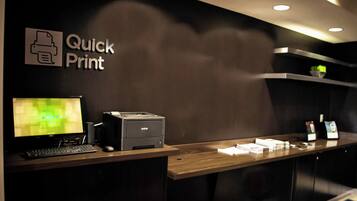 A reception desk with a monitor, printer, and a sign reading "Quick Print".