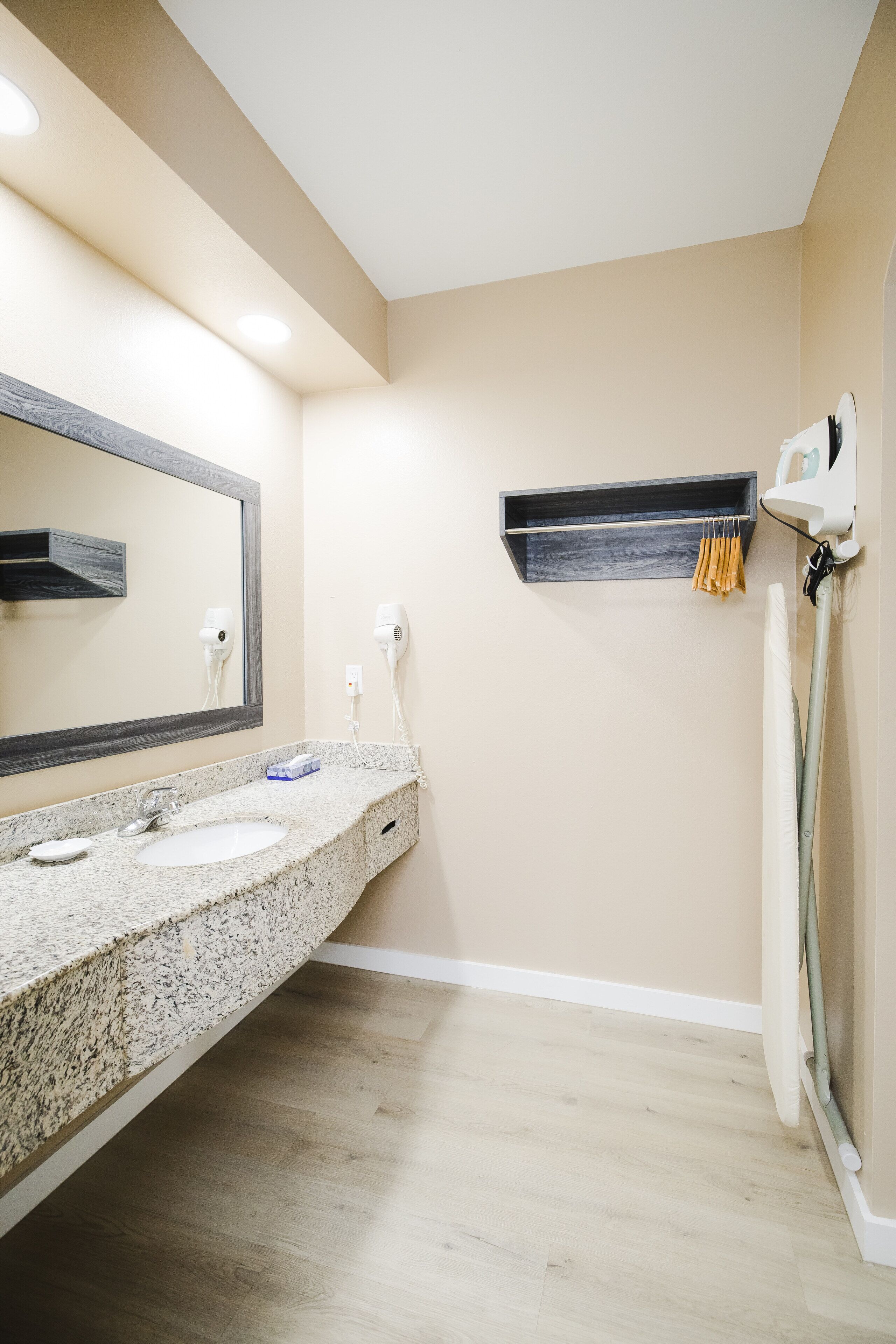 A bathroom with a granite countertop, two sinks, a large mirror, and a towel rack.