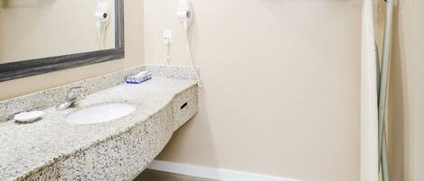 A bathroom with a granite countertop, two sinks, a large mirror, and a towel rack.