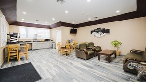A spacious living area with a dining set, sofas, and a television. - Sapphire Inn & Suites (Channelview)
