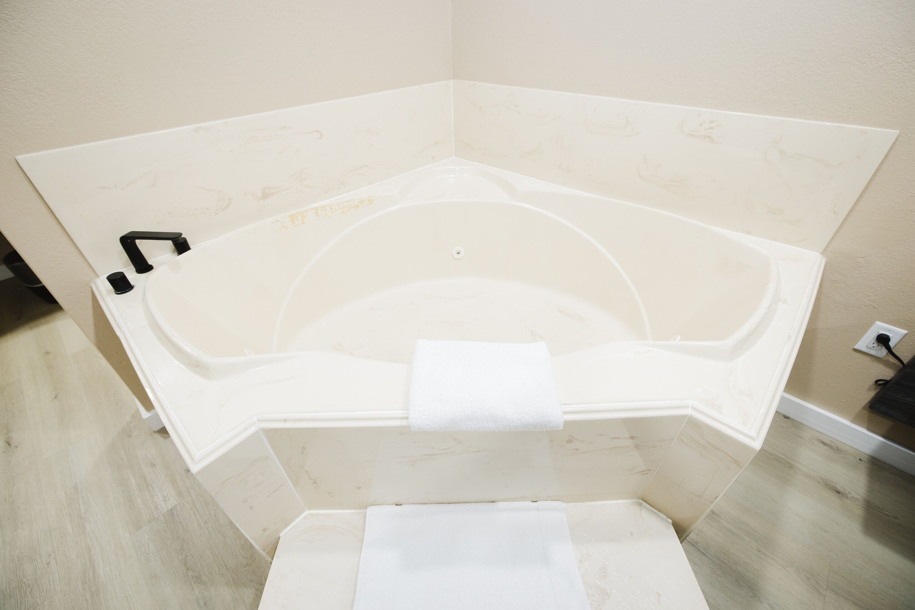 Un coin de pièce avec une baignoire, une serviette et une prise électrique au mur.
