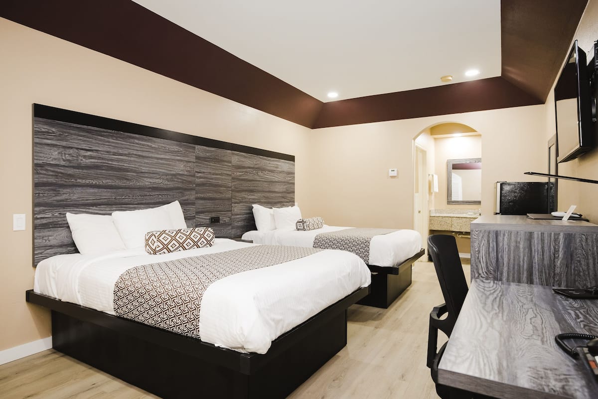 Ein Hotelzimmer mit zwei Betten, einem Schreibtisch, einem Stuhl und einem Fernseher.