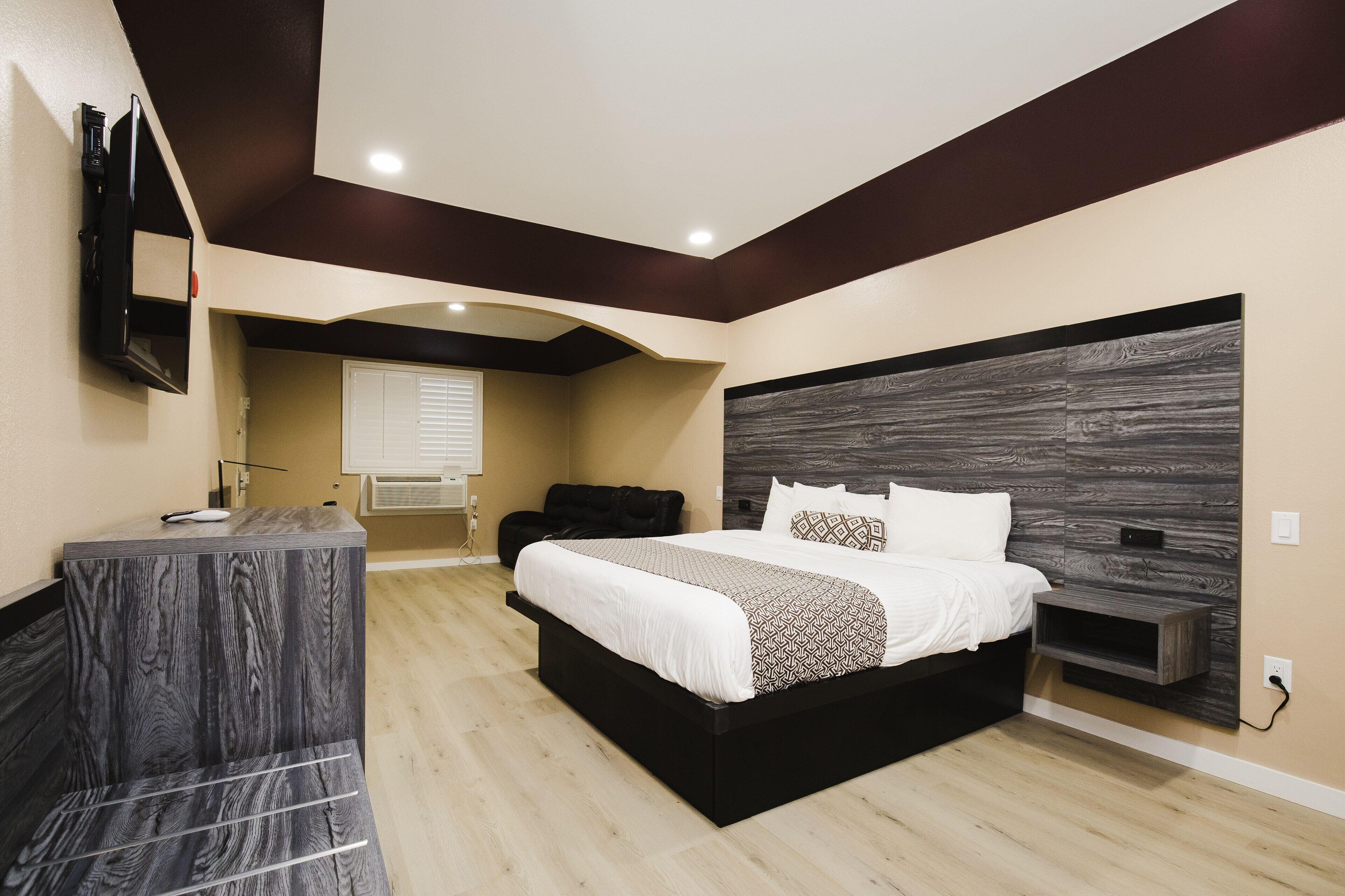 A modern bedroom with a large bed, a vanity, and a TV mounted on the wall.