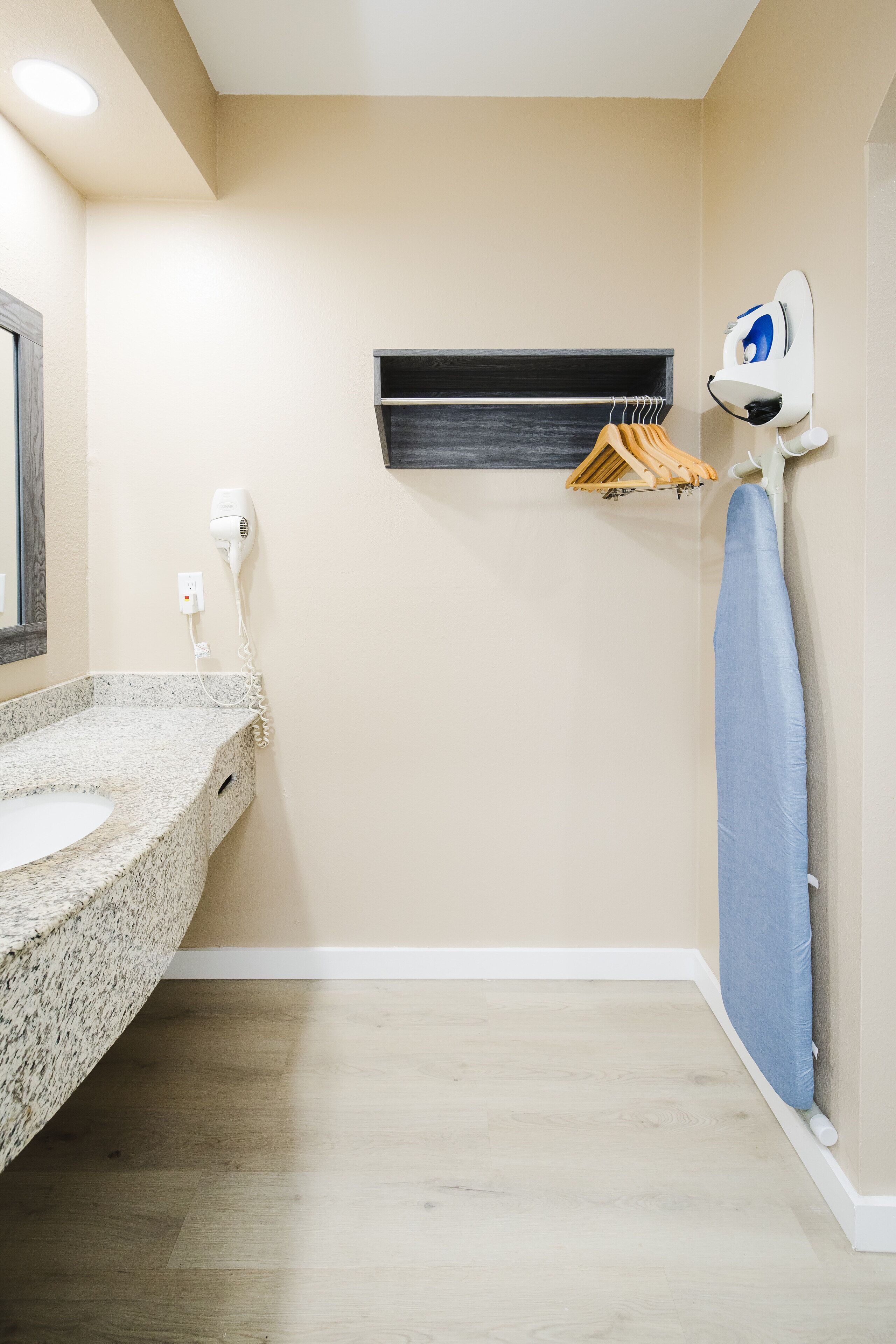 A bathroom with a granite countertop sink, a hairdryer, a towel rack, and a hanging towel.