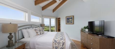 Une chambre à coucher comprenant un lit, une table de chevet, une commode, un téléviseur et un ventilateur de plafond.
