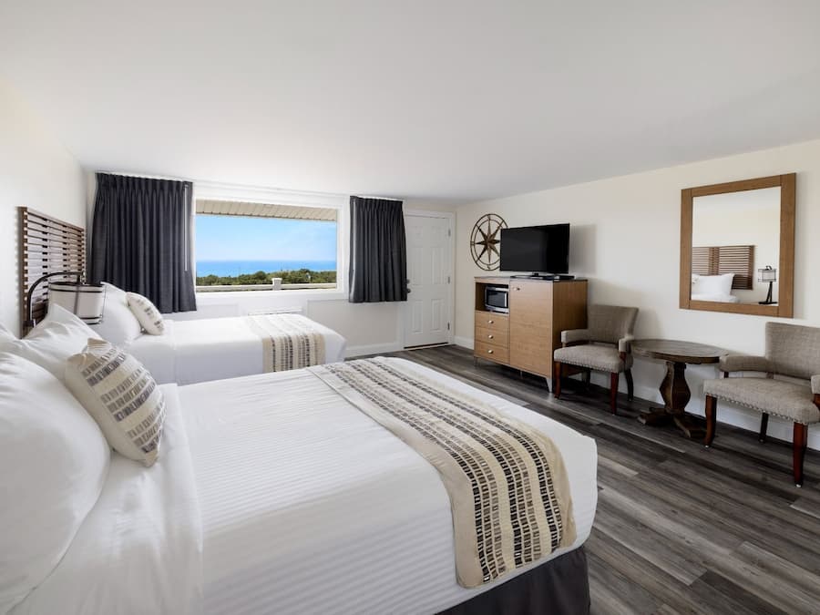 A hotel room with two beds, a TV, a desk, and a chair.