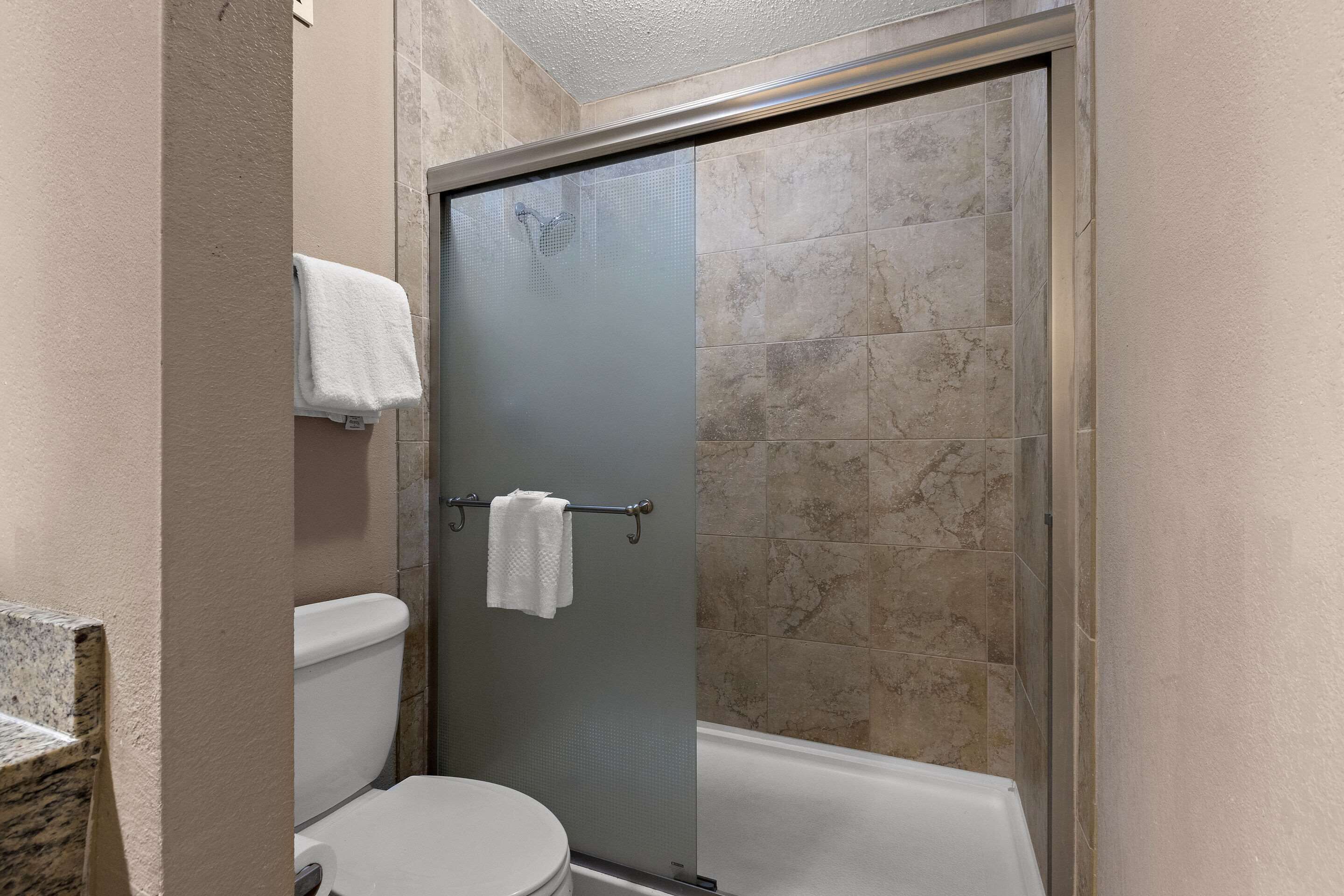 Un baño con cabina de ducha, inodoro y lavamanos.