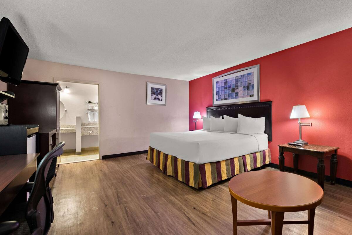 Quarto de hotel com cama, mesas de cabeceira, escrivaninha e uma cadeira.