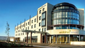 A modern hotel building with a curved glass facade, a covered entrance, and a sign reading "Maldron Hotel". - Maldron Hotel Sandy Road Galway (Galway)