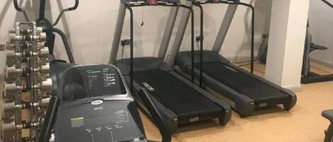 A gym with treadmills, a stationary bike, and a television on the wall.