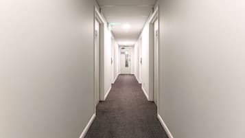 Un long couloir étroit aux murs blancs et au tapis sombre.