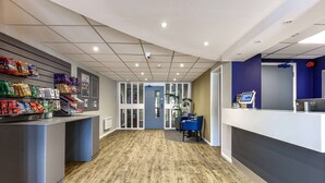 A reception area with a counter, seating, and a blue door labeled "Toilet Room". - Days Inn by Wyndham London Stansted Airport (Bishop's Stortford)