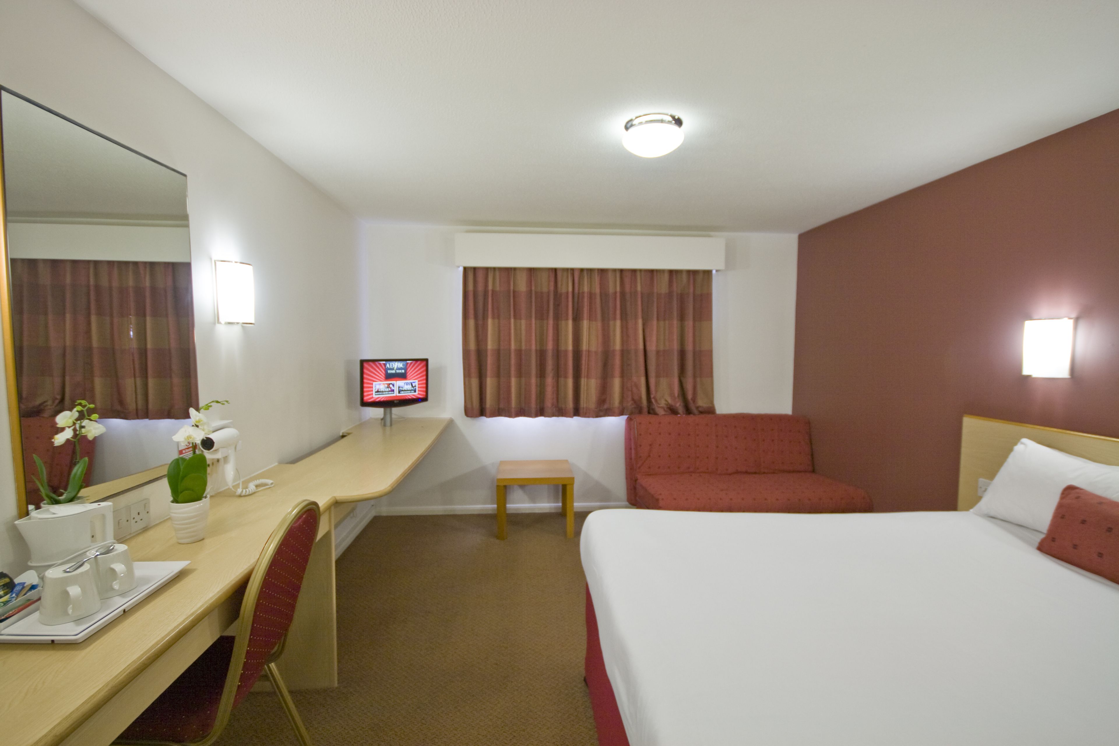 Una habitación de hotel con escritorio, silla, cama y televisor.
