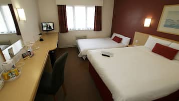 Une chambre d’hôtel avec deux lits, un bureau équipé d’un ordinateur, d’un téléphone et d’une télévision.