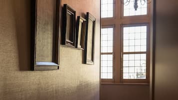 Ein Flur mit gerahmten Bildern an der Wand, einem gemusterten Teppich und einer Chandelier.