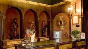 Una habitación con paneles de madera, un mostrador de recepción de mármol y estatuas religiosas.