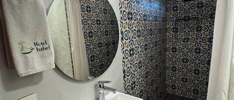 A modern bathroom with a white sink, mirror, and towel rack.
