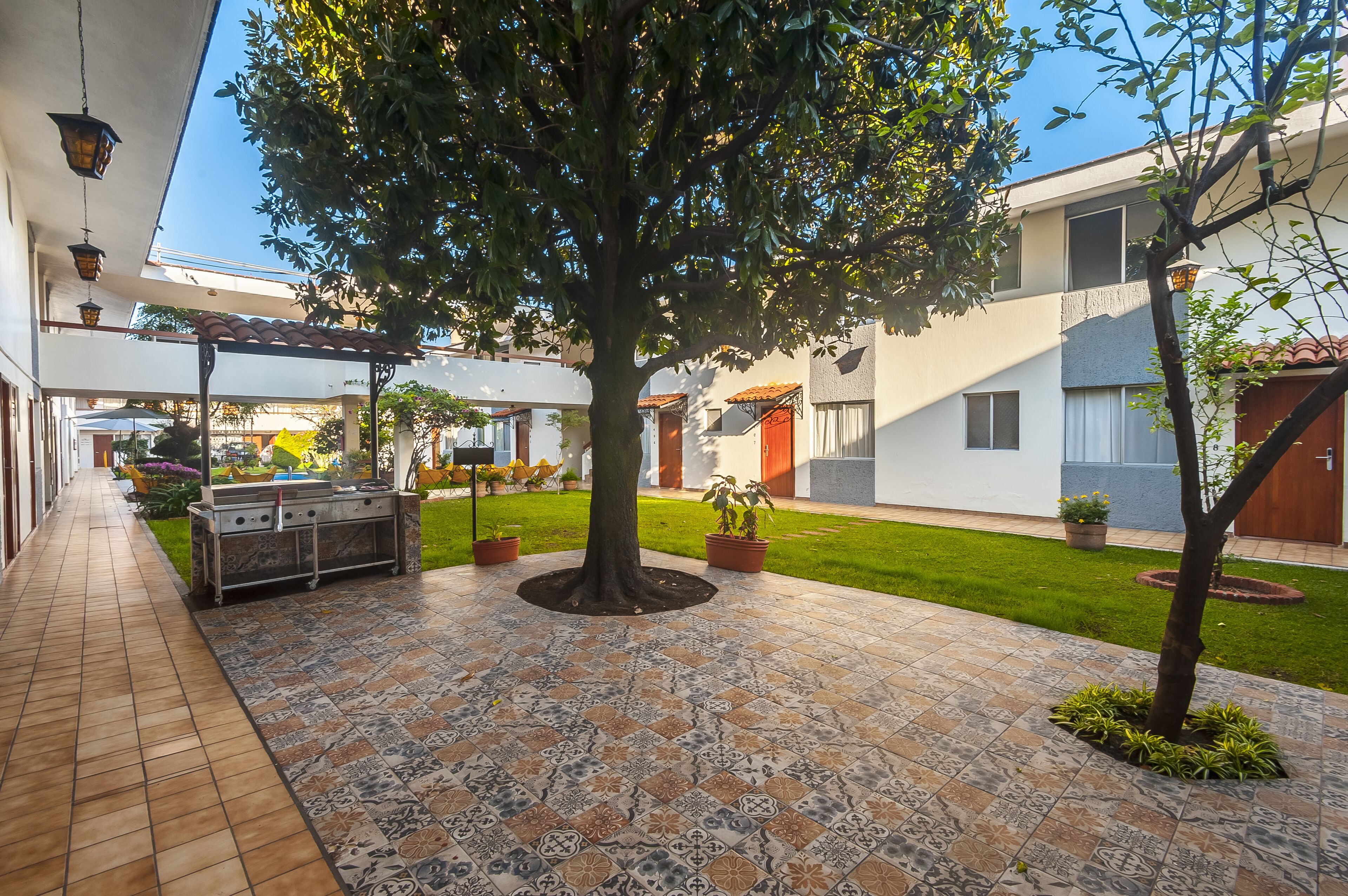 Ein Außenbereich mit Terrasse, Grill, Topfpflanzen und Fliesenboden.