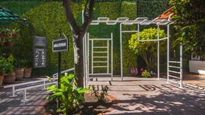 A fitness area with exercise equipment, a sign indicating 'AREA FITNESS', and a green hedge in the background. - Hotel Isabel (Guadalajara)