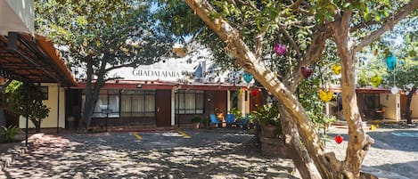 A building with a sign reading "GIALAJARA" and a stone pathway leading to a seating area with chairs and tables.