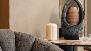 Un soggiorno moderno con un divano dalla superficie materassa, un tavolo in marmo e oggetti decorativi tra cui un vaso e una scultura in metallo originale.