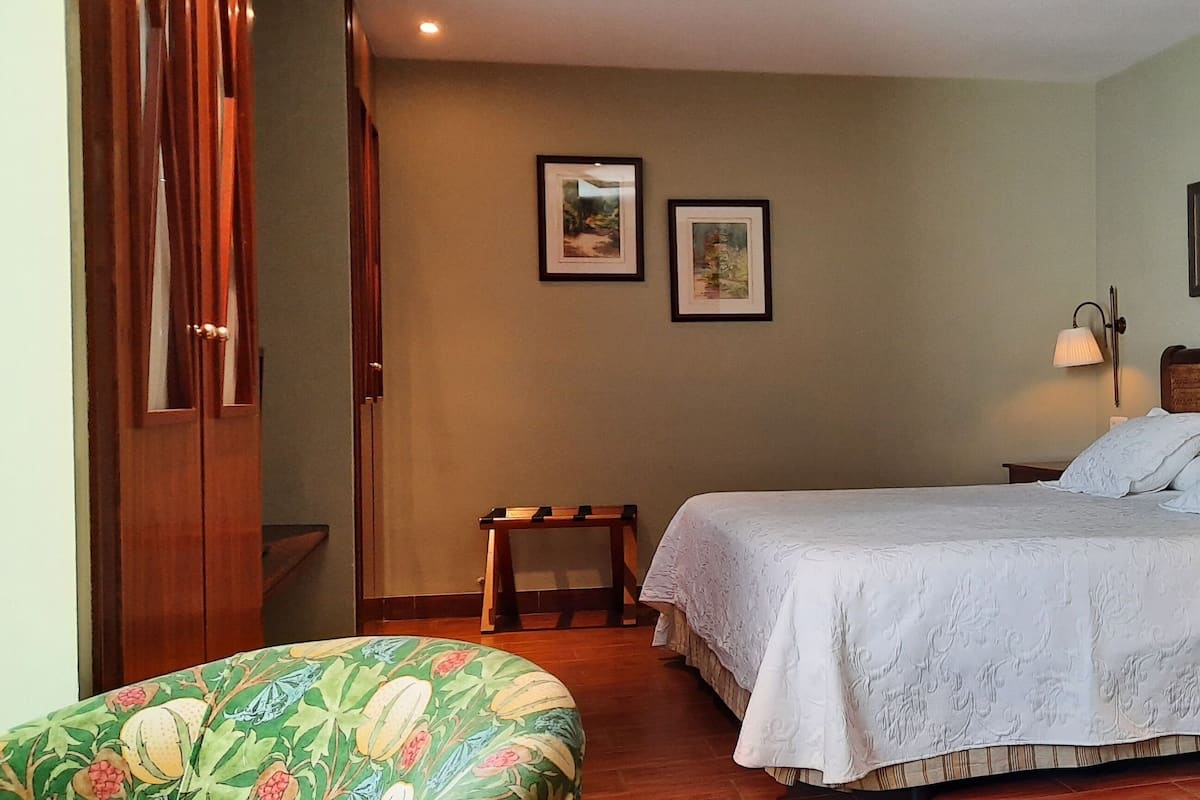A neatly arranged bedroom with a bed, bedside tables, a nightstand, and two wall-mounted lamps.