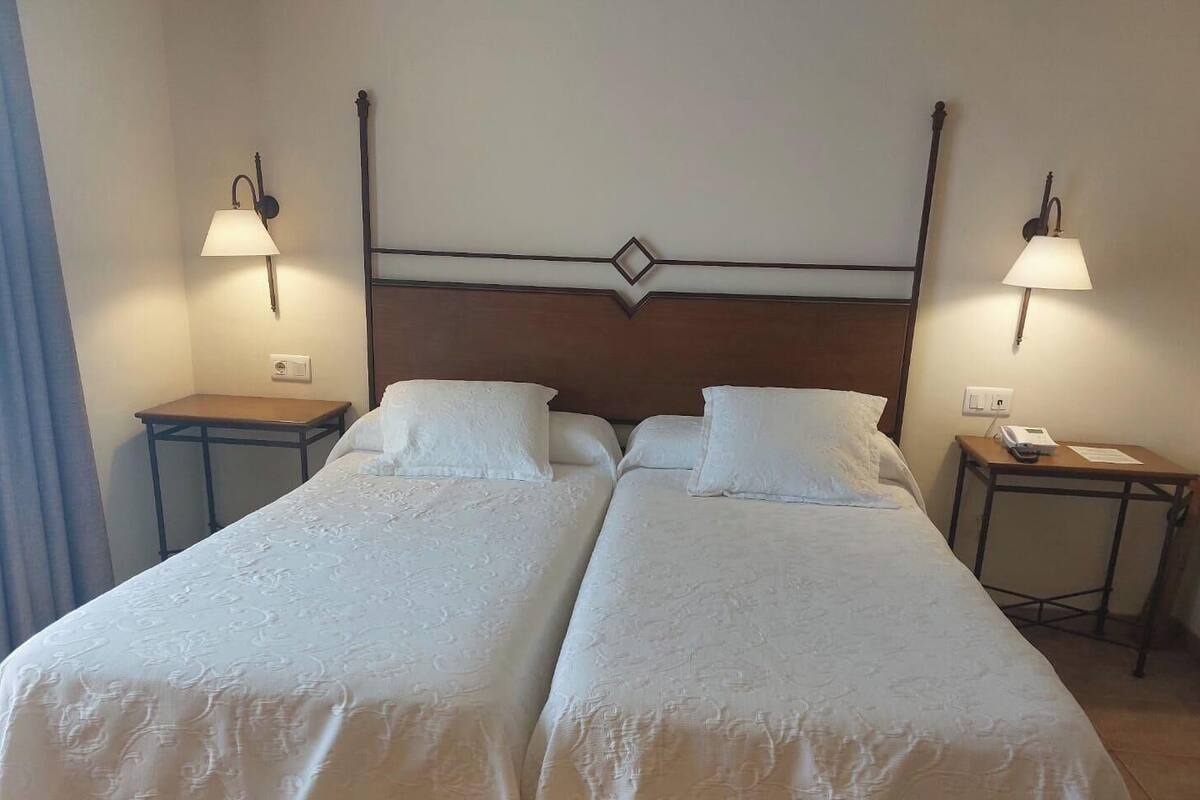A double bed with a wooden headboard, two bedside tables, and two wall-mounted lamps.
