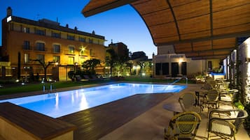 An outdoor swimming pool area with lounge chairs and a covered seating area.