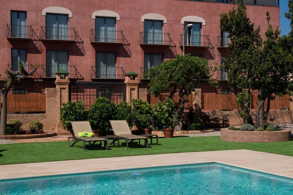 A poolside area with a rectangular pool, lounge chairs, and a building with multiple balconies.