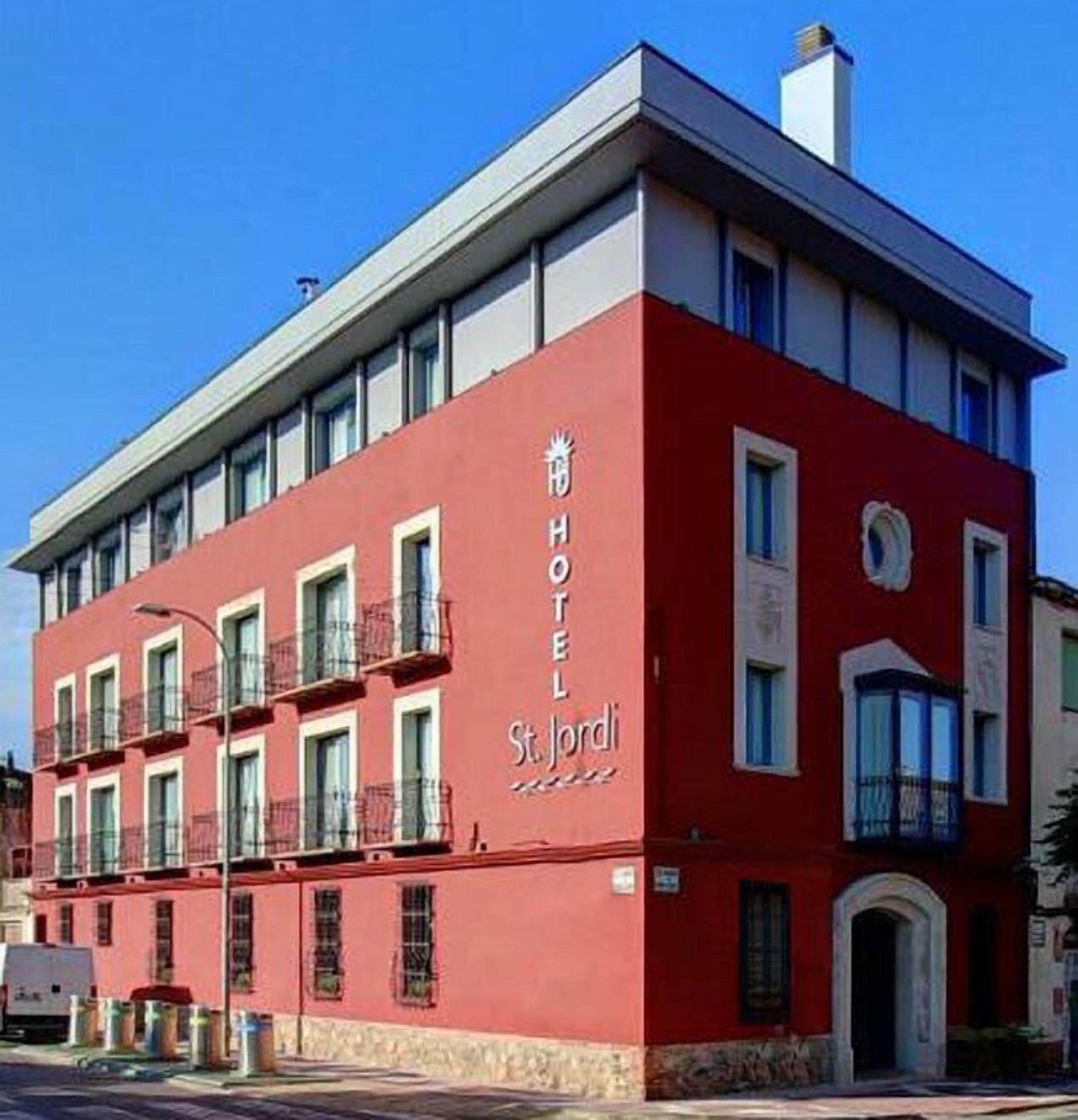 A red building with a sign reading "HOTEL St. Jordi".