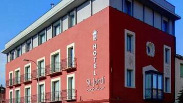 A red building with a sign reading "HOTEL St. Jordi".