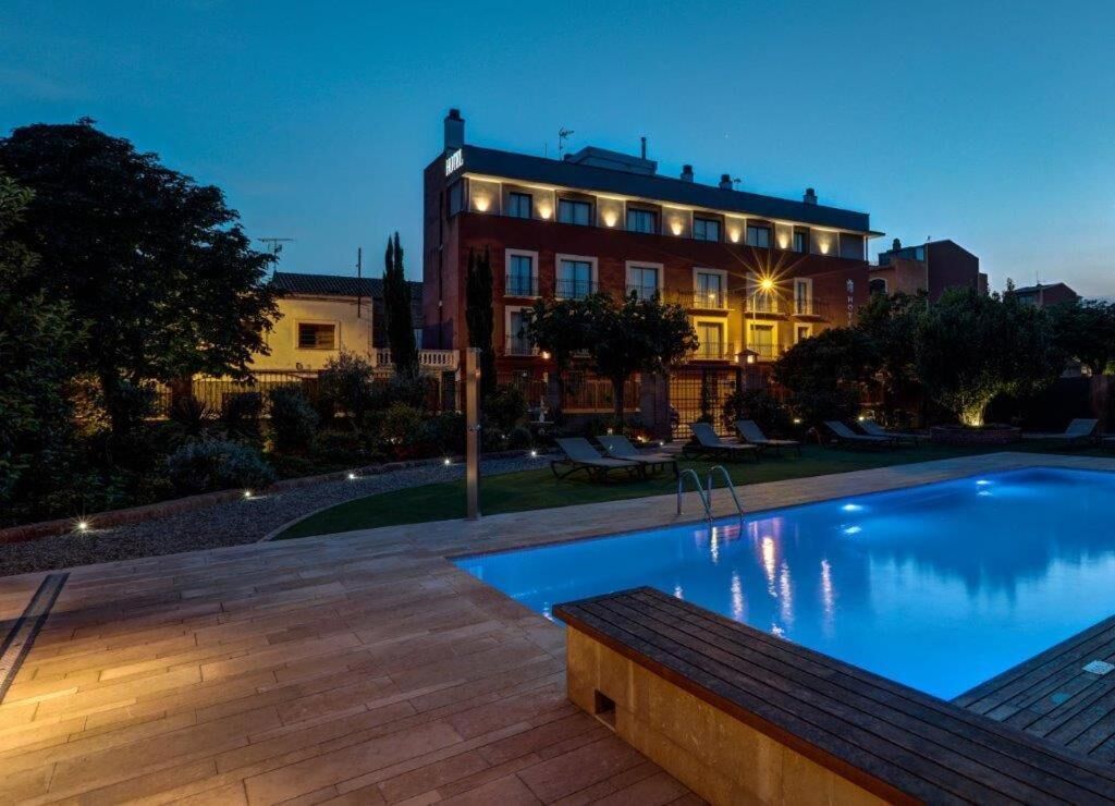 Un hotel con piscina, sillas de descanso al aire libre y una fachada bien iluminada.