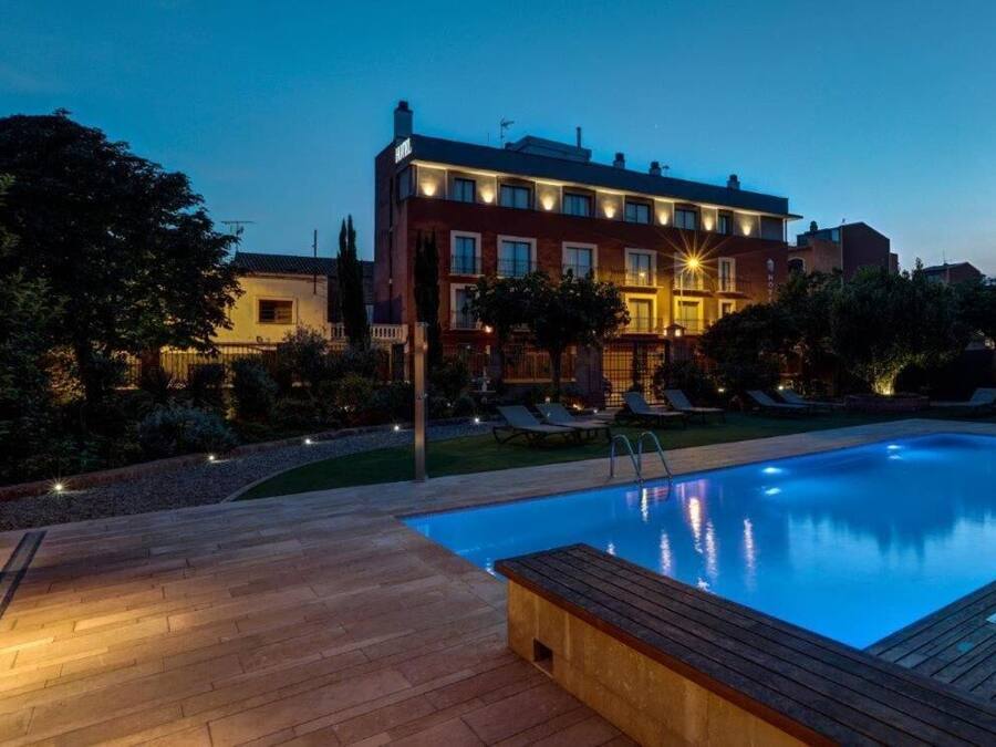 Un hotel con piscina, sillas de descanso al aire libre y una fachada bien iluminada.